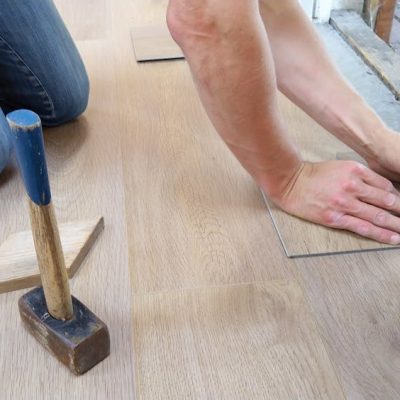 A craftsman carefully measures and marks wooden floor panels for precise installation.