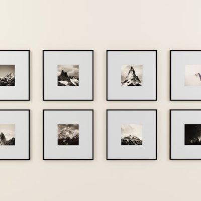 A minimalist display of framed mountain photography on a plain wall.